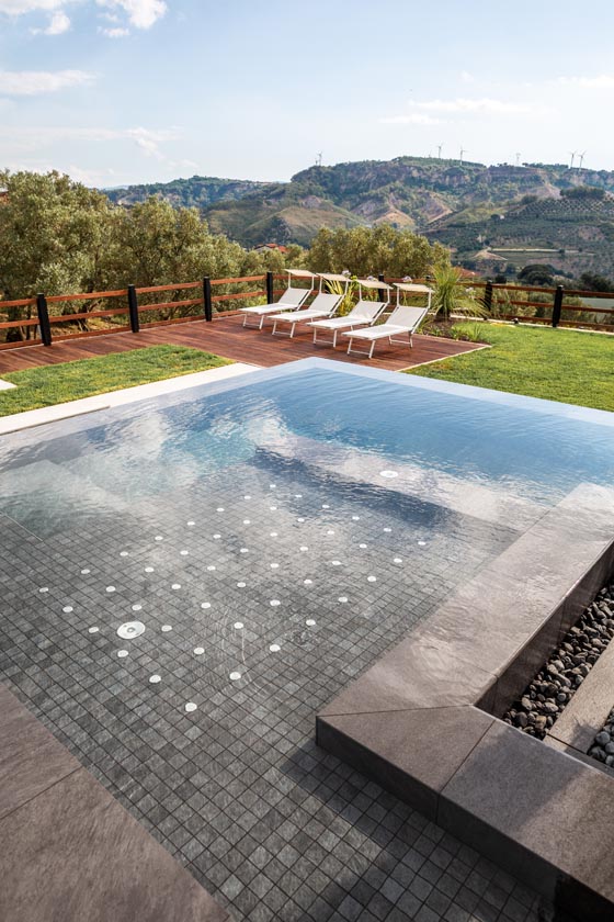 Piscina infinity a sfioro incastonata in un giardino collinare a Settingiano, Calabria.